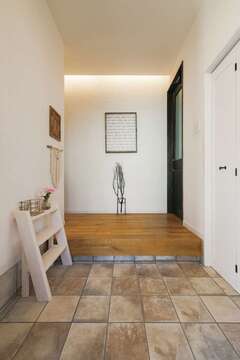 玄関正面の壁はコテ跡を残し、やさしい表情に。右手の扉は土間収納に続く