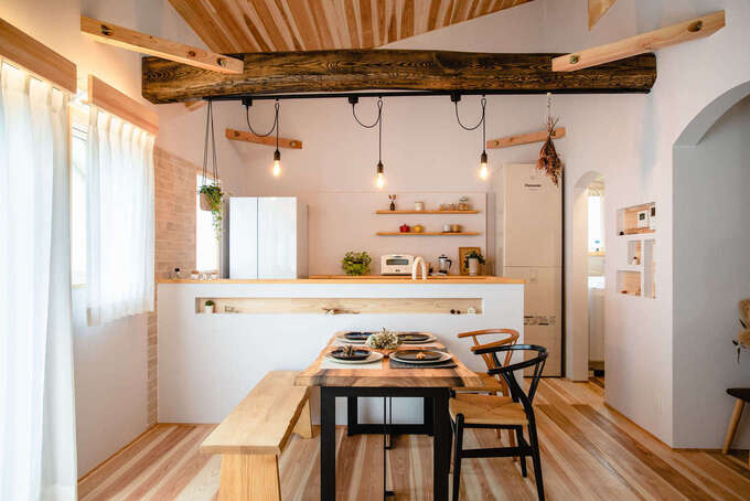 カフェスタイルのオープンキッチン。地熱利用の換気システムにより、レンジフードをつけなくてもにおいがこもらない。エコキュートを室内に設置することで保温の負荷が減り、年間の電気代が約1万4,000円も安くなるそう。太い丸太梁は『金澤建築』の代名詞で、家族みんなで塗装して家づくりの思い出に