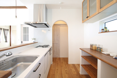 キッチンの背面には「見せる収納」を造作。キッチン奥に設けられたアーチ型の開口部はパントリースペースへとつながる