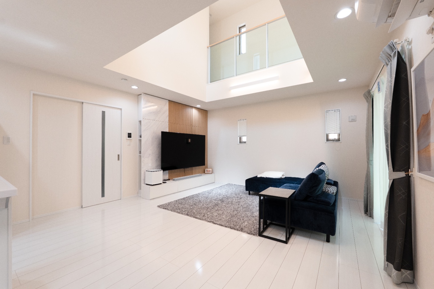 アイダ設計　｜広々としたLDKは吹き抜け天井が印象的で、開放感がある。モダンなインテリアが施され、落ち着いた雰囲気を作り出している。