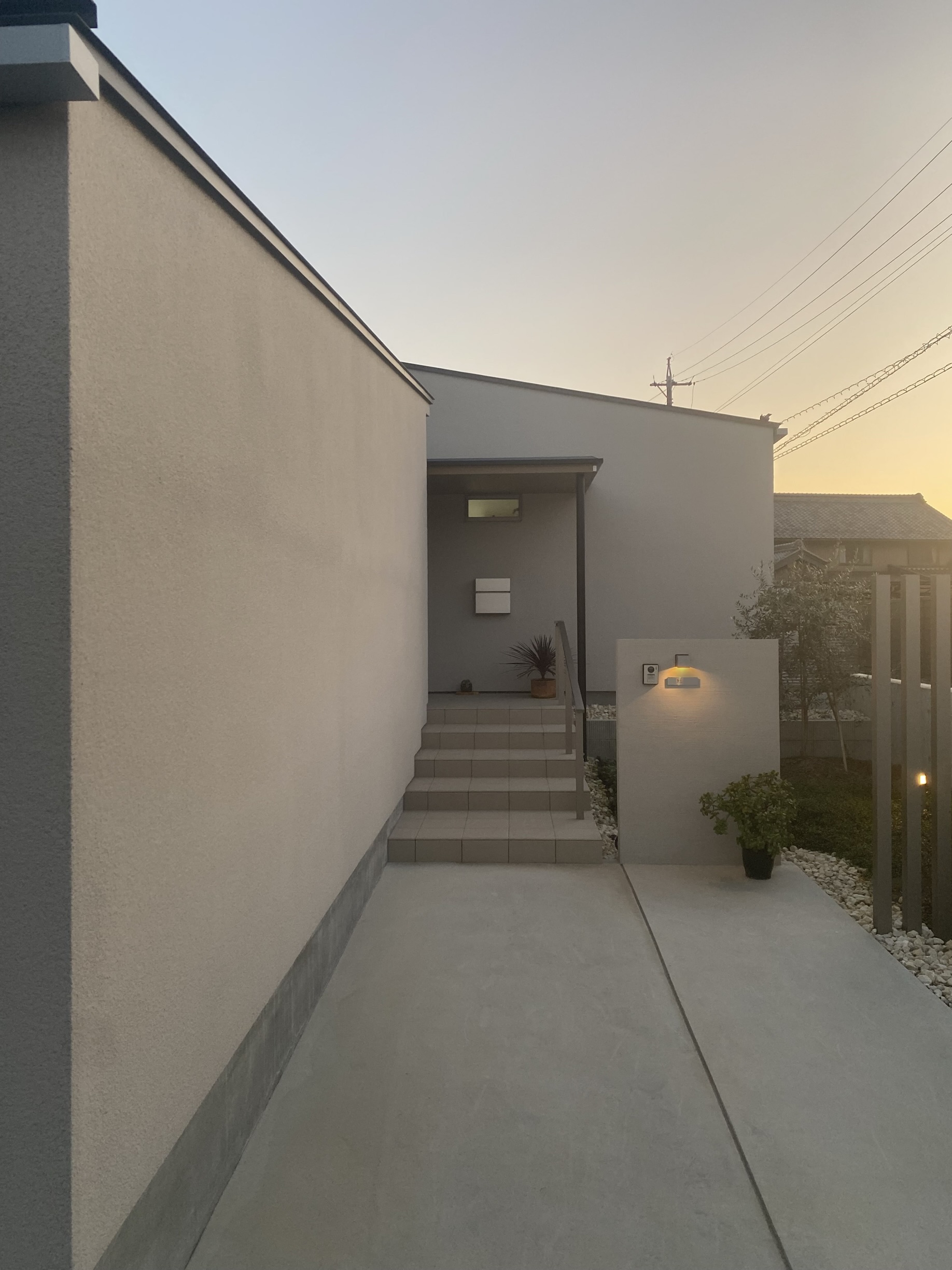 安田住宅｜安田建築設計室｜夕方の柔らかな光が玄関へのアプローチを優しく照らし、落ち着いた雰囲気を醸し出している。