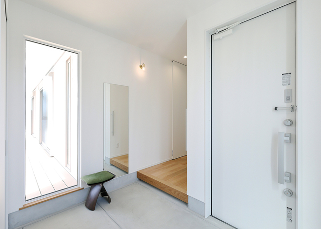 お庭を見渡せる大きな窓が印象的な玄関。たっぷりと光が入り、白が際立って明るく開放的な空間に