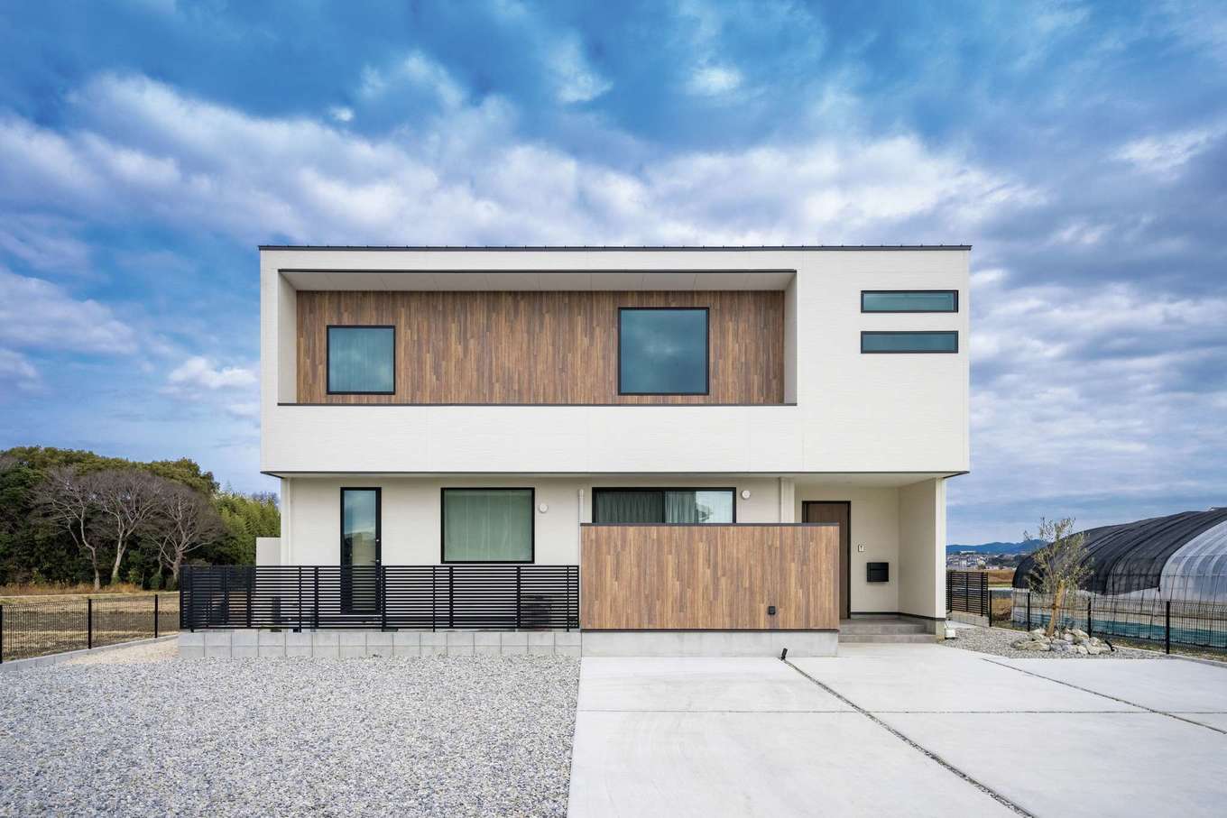 内田建設【デザイン住宅、間取り、建築家】タテ・ヨコのラインが美しいシンプル＆モダンな外観デザイン。外壁にアイボリーの塗り壁と木を取り入れたことであたたかみを感じられる。1階のウッドフェンスの裏がテラスデッキと庭になっている