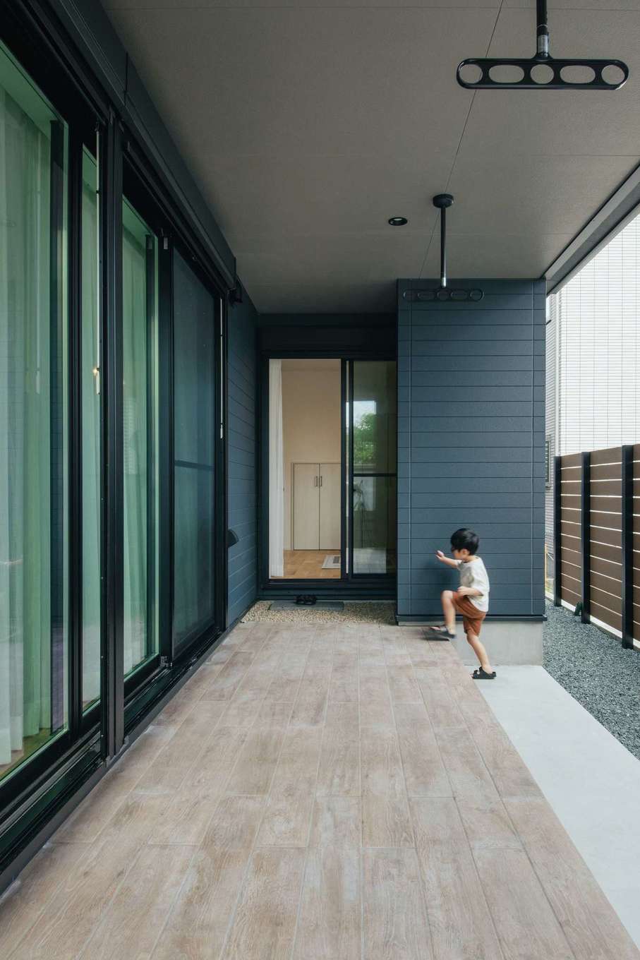 アイフルホーム焼津店 （三住建設）【デザイン住宅、子育て、収納力】リビングから続くテラスはアウトドアリビングとして大活躍。ウッドデッキは傷みやすくメンテンス費用がかかりやすいため、タイルデッキを採用した。フェンスも設置してあり、外からの視線を遮りながらBBQやプールを楽しむことができる。軒が深くて雨に濡れないので、天候を気にすることなく洗濯物を干したまま外出できる