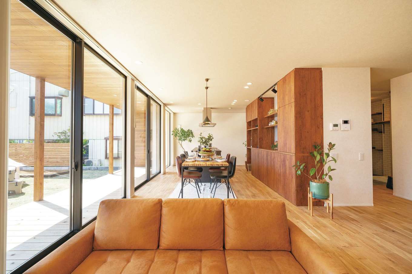 住家 JYUKA【デザイン住宅、間取り、建築家】大きな開口からたっぷりの光。要望に合わせて造作されたキッチンのバックセットが、オークと塗り壁がもたらすぬくもりと調和