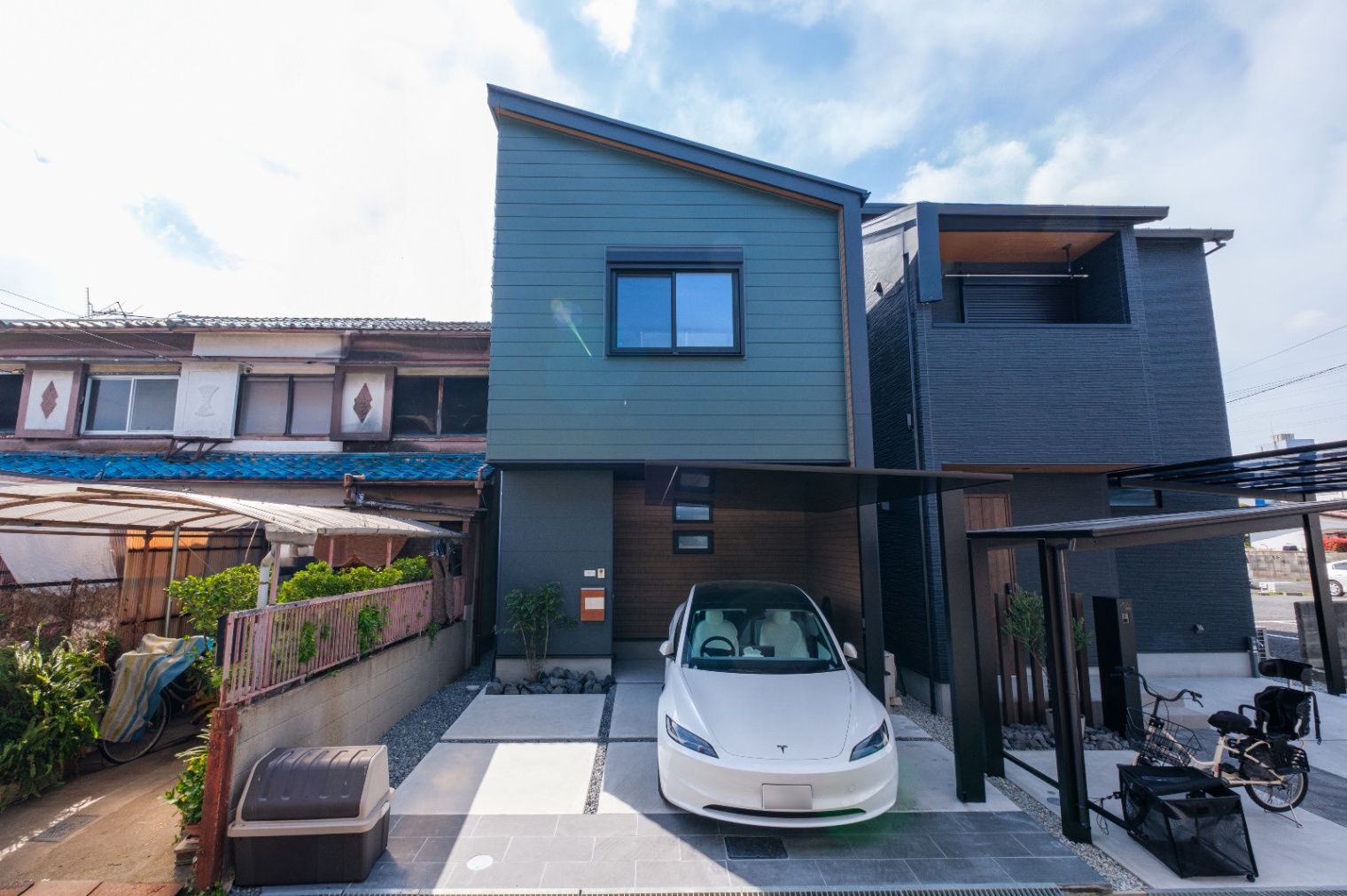 新栄建設｜スタイリッシュな外観。住まいの入り口には、電気自動車が停まるシンプルなカーポートが設けられている。