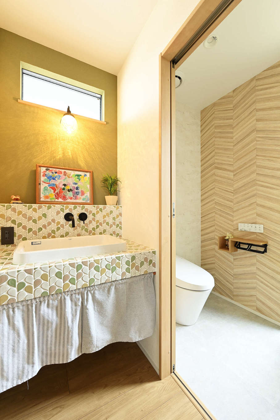 絆家（きずなや）【デザイン住宅、子育て、二世帯住宅】タイル貼りの造作洗面台は奥さまのこだわり。照明もイメージに合わせてセレクトした。トイレとのバランスも意識し、統一感のある雰囲気に。トイレにはスリット窓を設けてあるので、明るく清潔感に溢れた印象