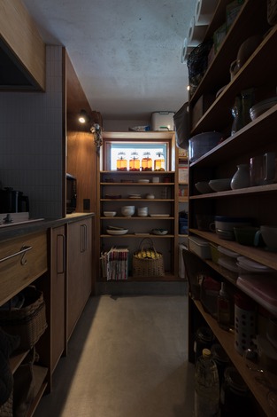 モルタル土間のキッチンは奥さまのお気に入り。冷蔵庫を中心に回遊できる空間は、全体がパントリーのような収納力。オープン棚で必要なものにさっと手が届く