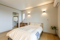 シンプルで落ち着いたインテリアが魅力の寝室。快適な眠りを提供するベッドと温かみのあるデスクが配置されている。奥のウォークインクローゼットは二人分の衣類が十分に収納できる広さがある。