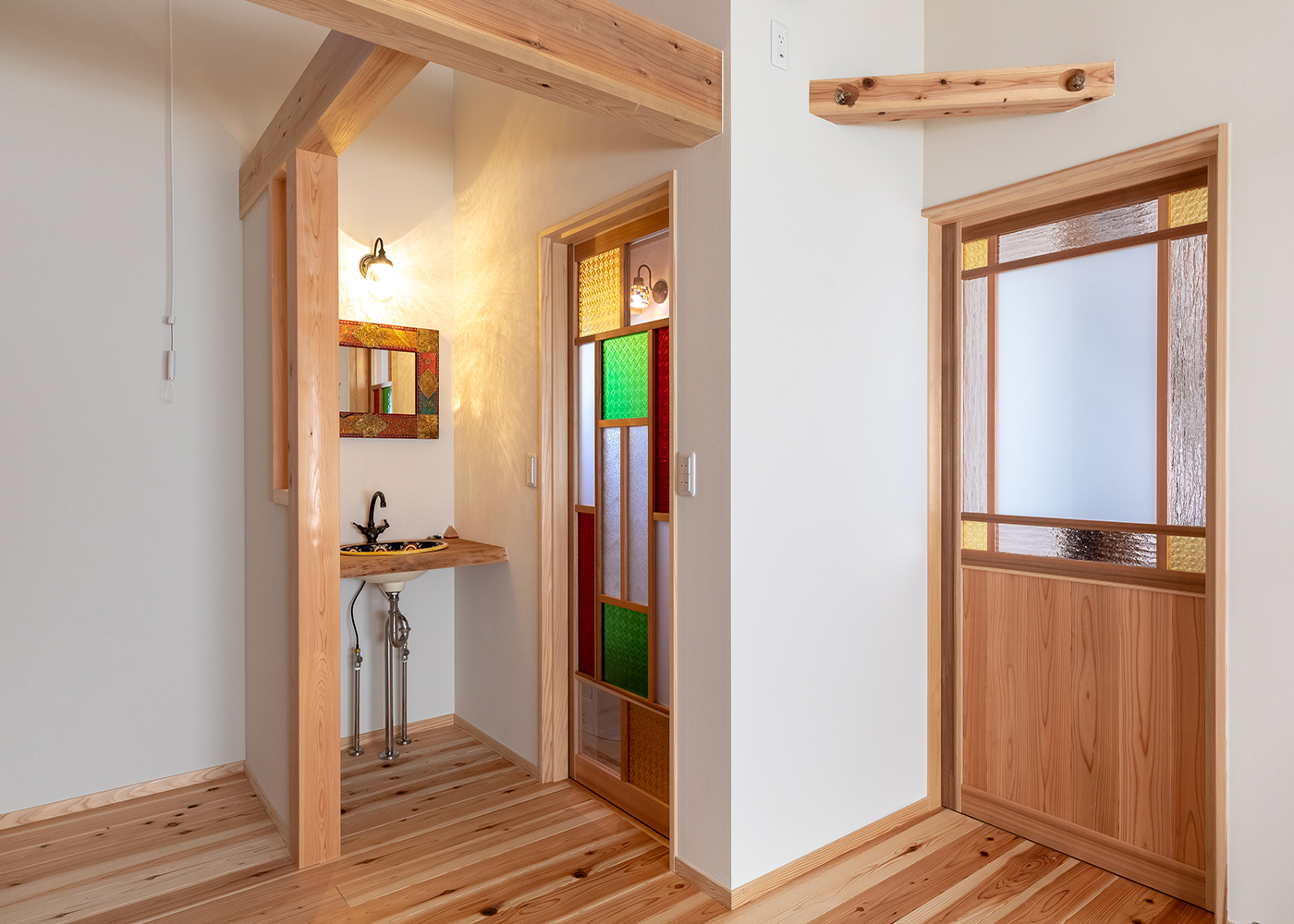 有吉住宅【趣味、自然素材、インテリア】2階の洗面とトイレは、アジアンテイストにコーディネート。蛇口や洗面ボウル、鏡、色ガラスを組み合わせた建具などで、ポップで明るく仕上げている