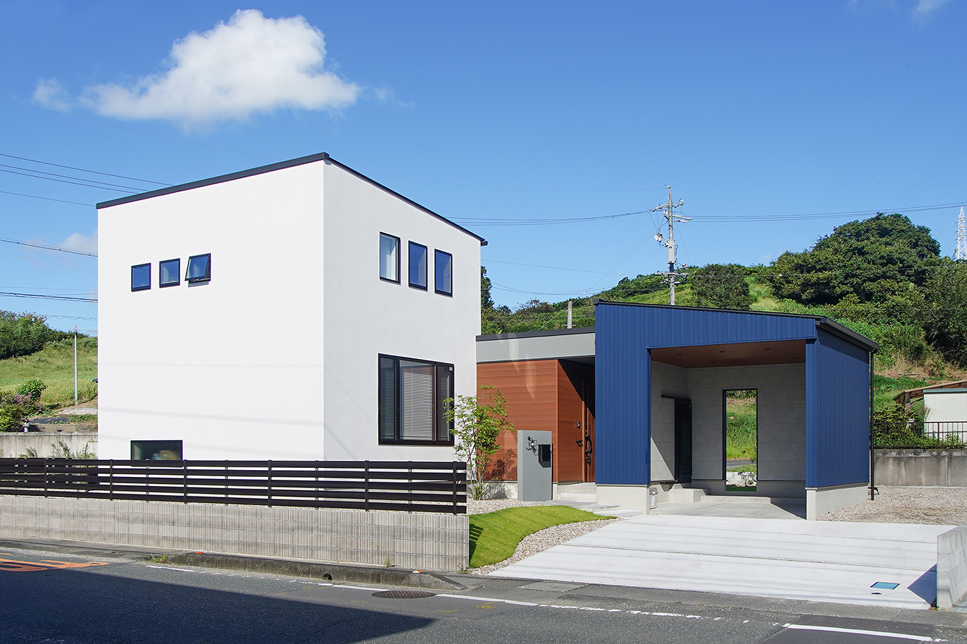 花みずき工房【自然素材、間取り、ガレージ】100坪以上のゆとりある土地に建てたK邸は、青い外壁材で仕上げられた大きなガレージが目を引く住まい。ガレージと住居をつなぐ通路は、シューズクロークとして活用。調湿・防虫作用のある無垢杉板を壁や天井に使った土間空間となっていて、室内干しもできる便利なスペースだ