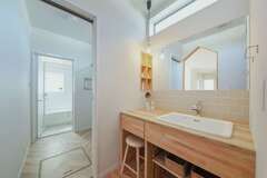 浴室、ランドリー、洗面、ファミリークローゼットを直線でつなぎ、洗う、干す、しまう家事動線がコンパクトに。リビングからも見えるオリジナル造作洗面化粧台は、デザインにこだわって非日常感を演出している