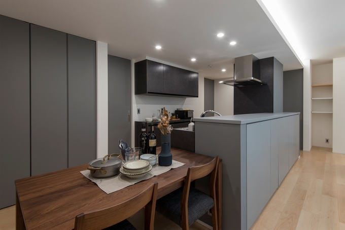 モダンな雰囲気に仕上げたダイニングキッチン。ダイニングテーブルを横並びにしたことでリビングを広く使えると同時に家事効率もUP。パントリーを建具で隠して生活感を出さない工夫も