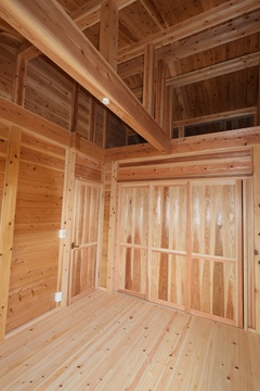 天然木をふんだんに使用した居室。高い天井と木の温かみが感じられる空間が広がり、リラックスできる雰囲気を演出している。