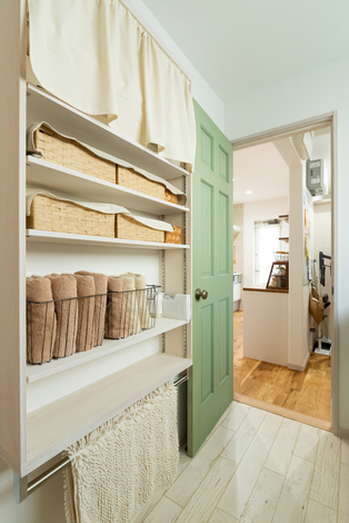 背後には収納棚を設置し、物が増えがちな洗面所の整頓を叶える。布で目隠しすることで柔らかい印象となった