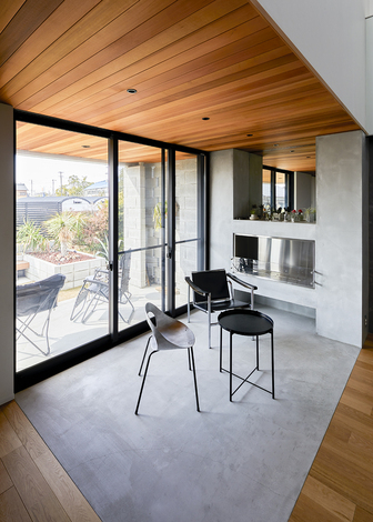 リビングとフラットにつながるモルタルの土間スペース。壁にバイオエタノール暖炉を設け、冬でも暖かく過ごせる。窓を開ければ、外のテラスとも一体化し、開放感が倍増する