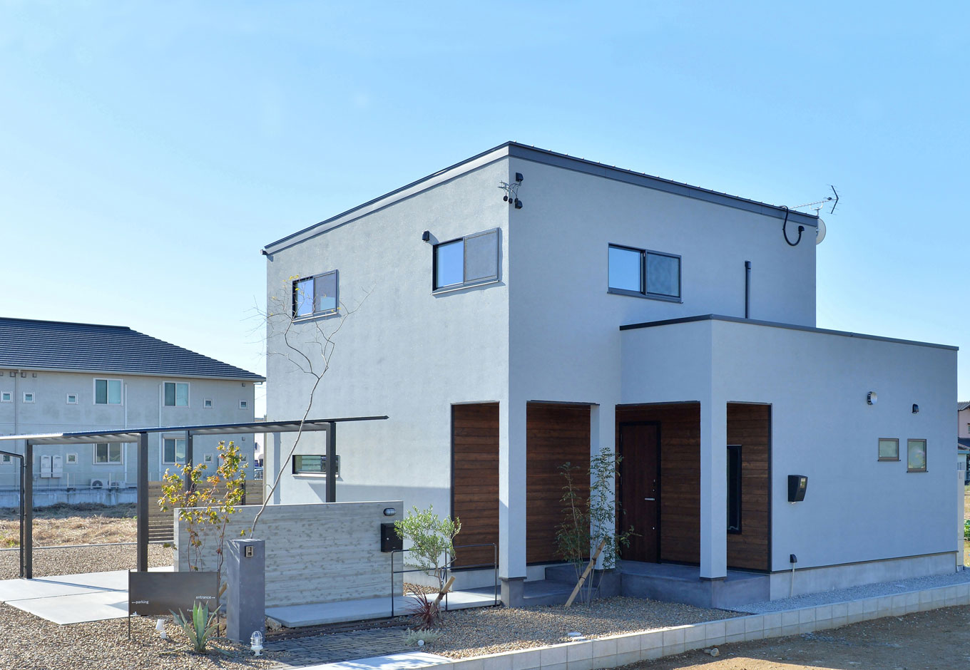 ARRCH アーチ【デザイン住宅、子育て、建築家】広くて開かれた土地の利を活かし、室内が圧迫感なく外へとつながる大空間をデザイン。玄関へのアプローチは素材にこだわり、あえて細く奥まったスタイルにしたことで、玄関からLDKに入った時のワイドなインパクトを強調した