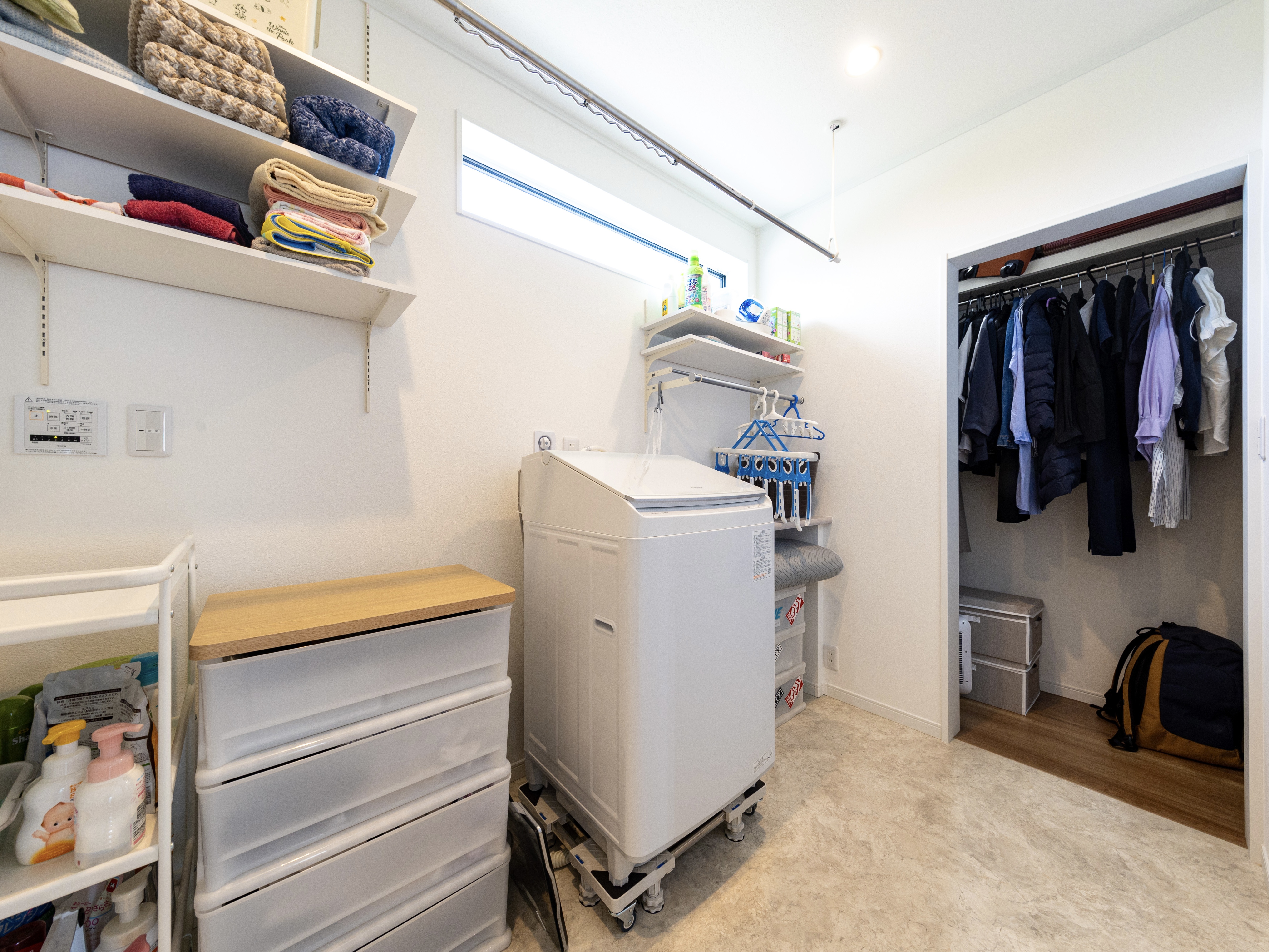 エスホーム｜洗濯機や収納棚が設置されたランドリールーム。衣類を効率よく整理できるクローゼットも併設されており、家事動線がスムーズ。