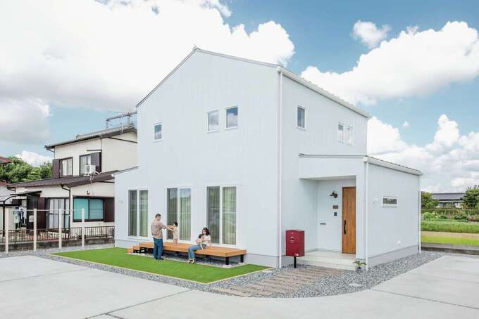 約96坪の広い敷地に立つW邸。青空や芝生の緑に映える真っ白な外観がインパクトを放つ。外壁もサッシも白で統一したのは、デザイン担当の奥さまのこだわり。休日にはウッドデッキに出て家族でのんびりくつろぐ楽しみも増えた