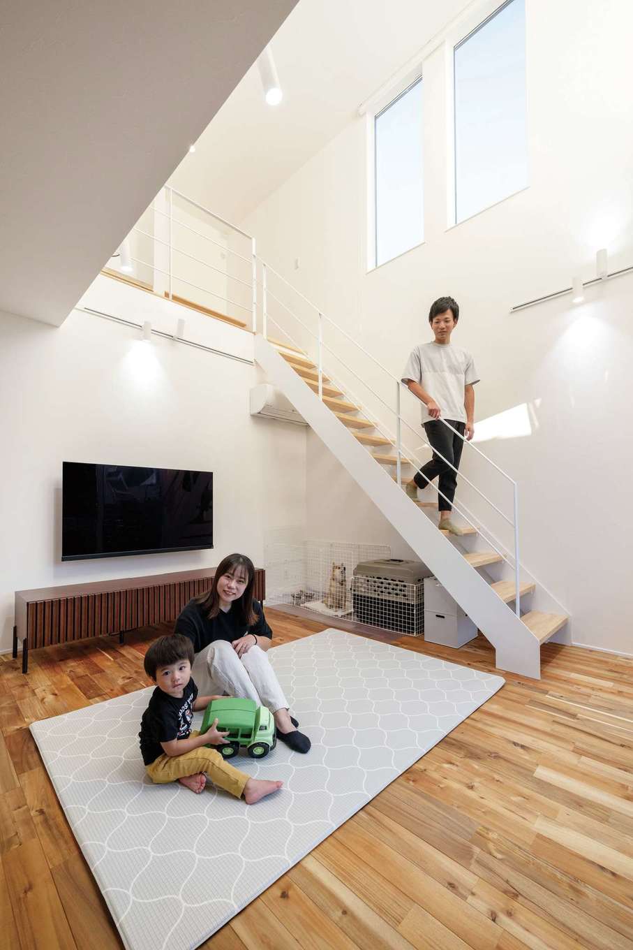 ハウスプラン（R＋house沼津・富士）【デザイン住宅、省エネ、建築家】家族でゆったり過ごすリビングは開放的な吹抜けに。家中が快適な空気で満たされているのは、高い住宅性能と、この吹抜けのおかげ。床材は色と質感が気に入って採用したアカシアの無垢材。クロスは北欧テイストが好きな奥さまのチョイス