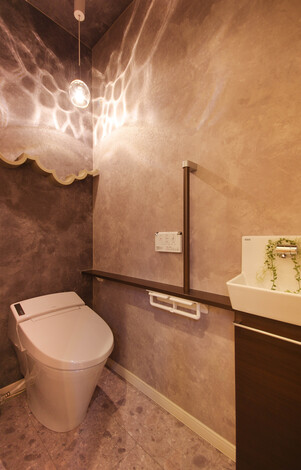 おしゃれな照明と壁の装飾が特徴的なトイレ。落ち着いた雰囲気で、リラックスできる空間である。