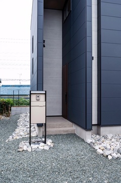 ダークカラーの外壁にセメント調のアクセントが映える。