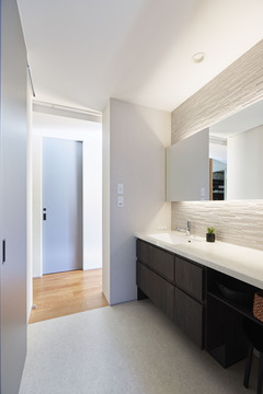 洗面は、大きな一枚鏡の背面に間接照明を組み込み、壁はタイル張りに。「ホテルライクなテイストにしたくて」と奥さま。