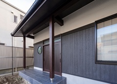 伝統的な日本家屋を彷彿とさせる外観。ホワイトのサイディングと木目のサイディングを幕板で継ぎ合わせている。また玄関横の丸窓が可愛らしく特徴的。