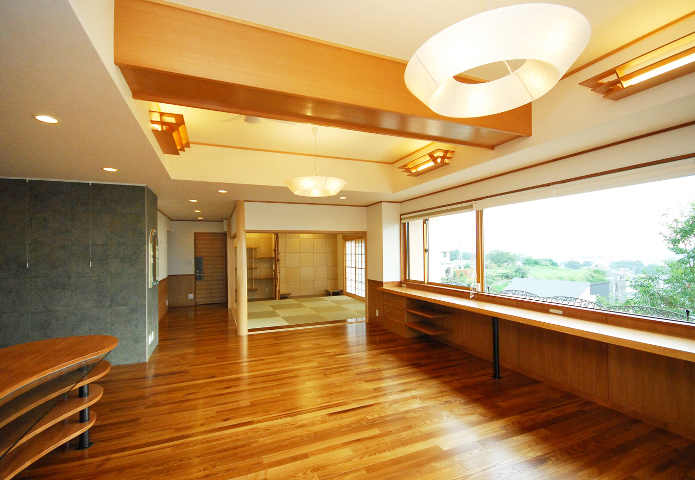 一級建築士事務所 GO_AN (ゴアン)｜大きなピクチャーウインドウの前には引き出し付きの無垢板カウンターを設置。照明器具も『GO_AN』がデザインし、大工と一緒に制作