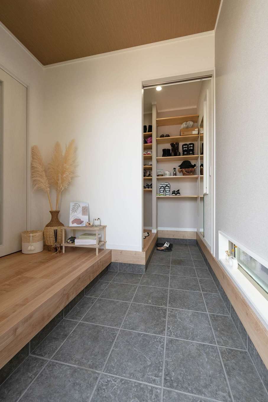 サンワ開発【デザイン住宅、収納力、間取り】足元のスリット窓は、プライバシーを守りながらも玄関に光を取り入れる。家族の日常動線はシューズクロークを利用して、いつもすっきりと保つ