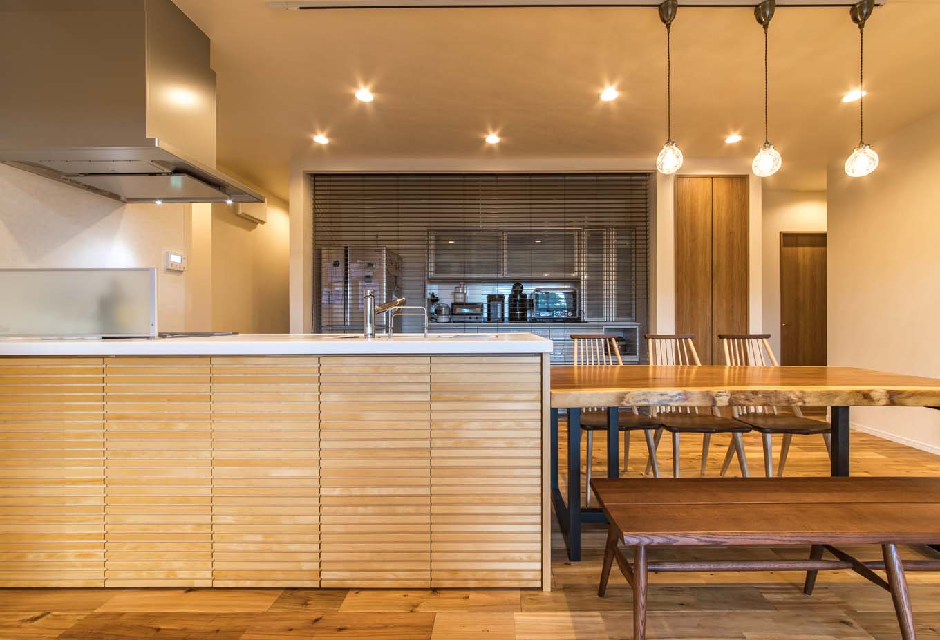 KOUBOU STYLE 建築工房相良（FPの家）【デザイン住宅、収納力、平屋】料理好きの奥さまのお気に入りは、ゆとりのスペースを確保したキッチン。背面の収納は冷蔵庫からキッチン家電まで収納し、必要時以外は木製ブラインドで目隠し。オープンキッチンのカウンター下は収納を造作した