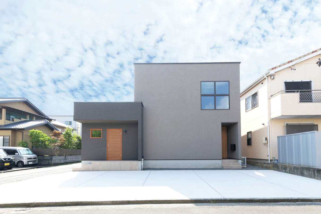 住家 JYUKA【デザイン住宅、趣味、間取り】グレーの塗り壁と十字窓が印象的なファサード。住居とスタジオスペースをきっちり分けるため、2つの玄関が設けられている。生徒さん用も含め、5台分の駐車場が用意された