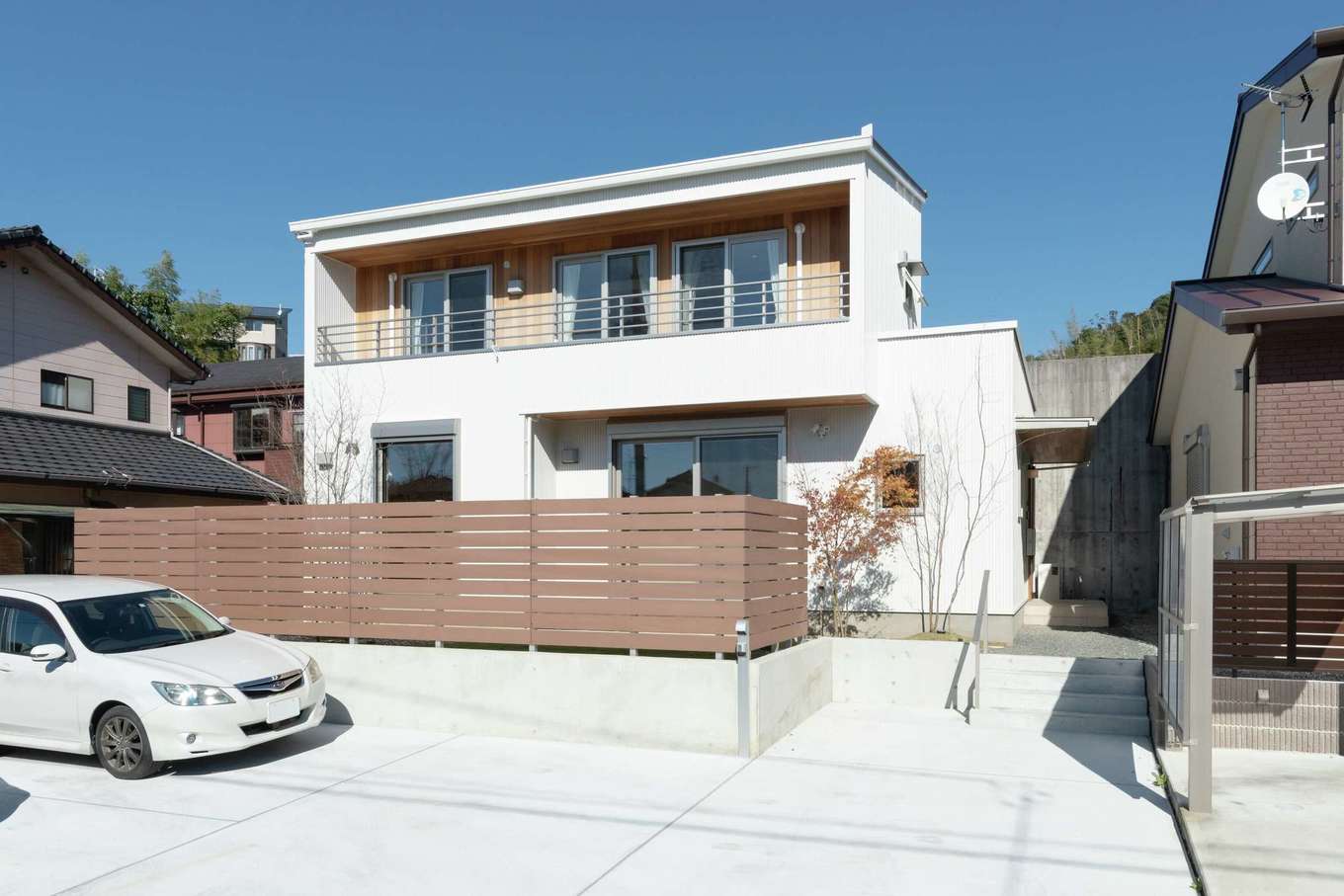 仲田工務店【自然素材、省エネ、間取り】白ガルバリウムにレッドシダーが映えるすっきりとした外観。庭は板塀で囲って道路からの視線をカット