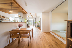キッチンの天井は床と合わせて木目にし、木の素朴さと温かみが伝わる優しい空間を演出。ダイニング側から調理台が見えない様にキッチンの腰壁を高くして生活感を隠し、カフェ風のオシャレなダイニング空間が実現