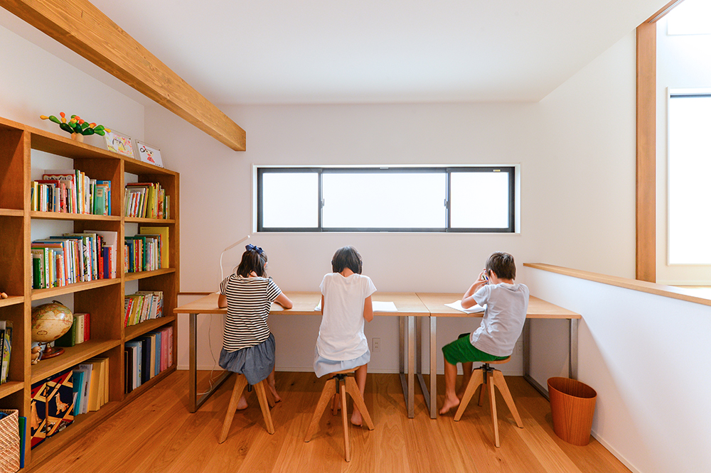CSホームズ｜明るい窓際に設けられたスタディスペース。子どもたちが集中して学習できる広々としたカウンターと本棚が特徴で、学びを促進する空間。