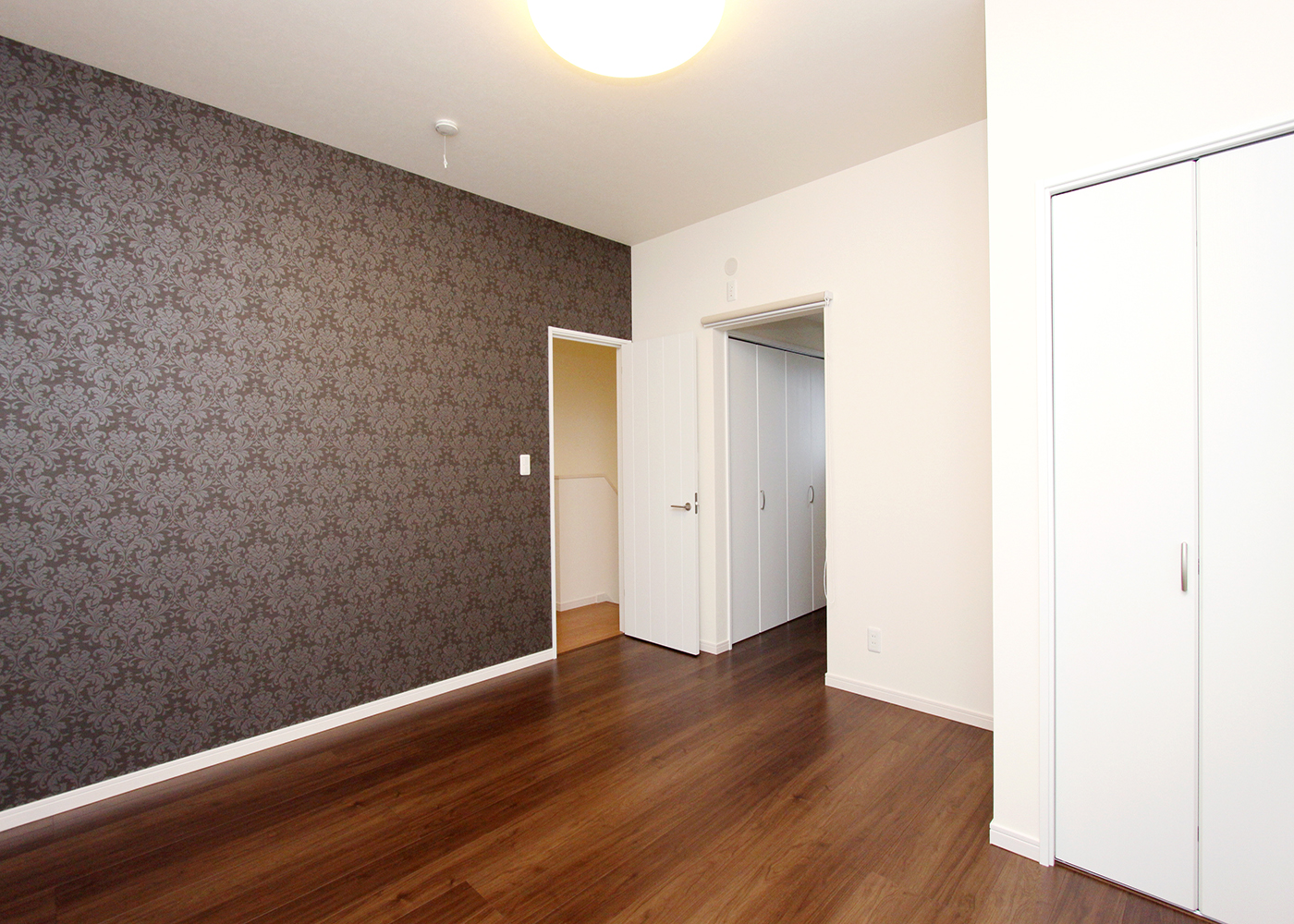 丸昇彦坂建設【デザイン住宅、間取り、インテリア】木調の床材と白のクロスで一体感を生み出しながらも、自身の存在感を誇示するヨーロピアンなアクセントクロス