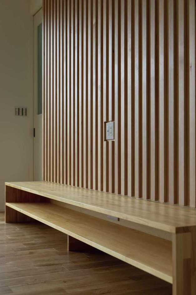 奥さまの友人宅で一目惚れした木の格子をテレビの背面壁に採用。同社