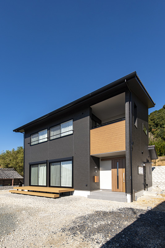 トキワハウス デザイン アンド ビルド（常盤工業）｜モダンなデザインの二階建て住宅の外観。ダークカラーの外壁にウッド調のアクセントが美しく調和している。