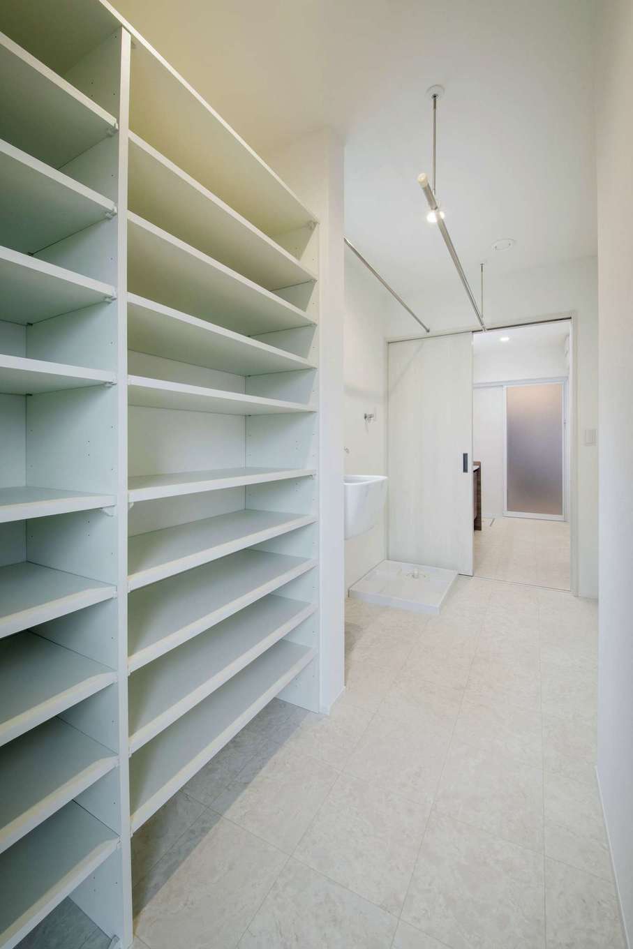 桜建築デザイン【デザイン住宅、子育て、間取り】キッチンから洗面スペース、ランドリーへと回遊でき、家事動線がスムーズに。「キッチンから3秒で移動」という奥さまの目標を見事にクリア。ランドリーには室内干しのほか、下着やタオル類などをたっぷりしまえる造作の収納棚も確保した