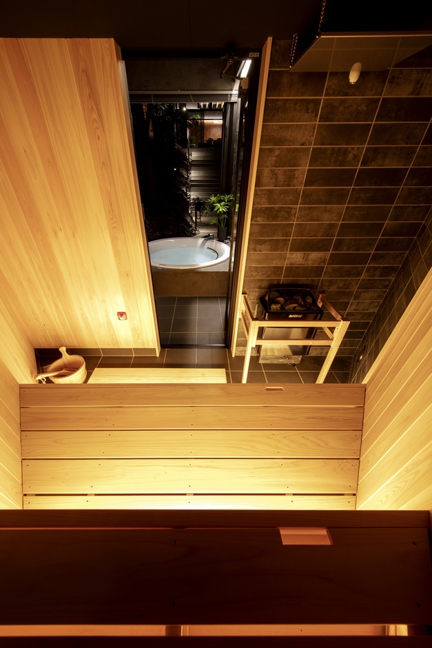 落ち着いた色調のサウナ室。木材とタイルが統一感を持ち、リラックスできる雰囲気を演出している。サウナ室を出た先には浴槽があり、ラグジュアリーな時間を楽しめるデザイン。