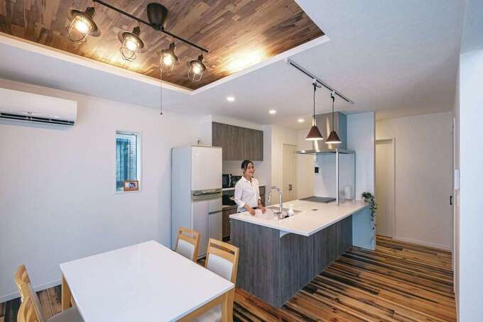 ペニンシュラ型のフラットキッチンは壁の向こう側を通って回遊できる仕様。ダイニングの上は間接照明付きの折り上げ天井に