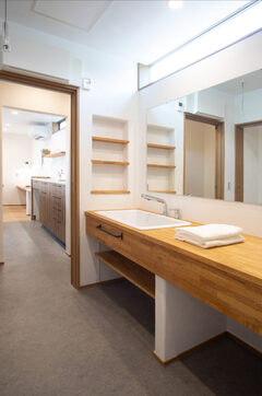 大型のシンクを備えた造作洗面台を設けた、3帖ほどの洗濯洗面脱衣室。脱着式の天吊り型物干し「ホスクリーン」を備えて部屋干しも行える洗濯洗面脱衣室は、調湿性に優れた珪藻土の塗り壁で仕上げられている。