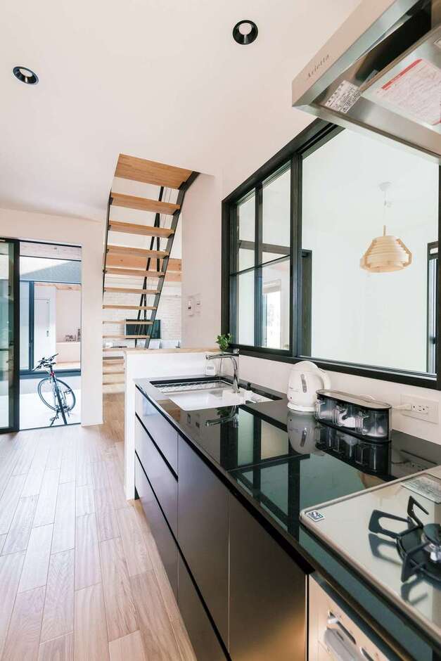 『納得』オリジナルのキッチン。高級感のある御影石とマットブラックのパネルがシックで美しい。和室、中庭、勝手口からも光が入る気持ちのいい空間だ