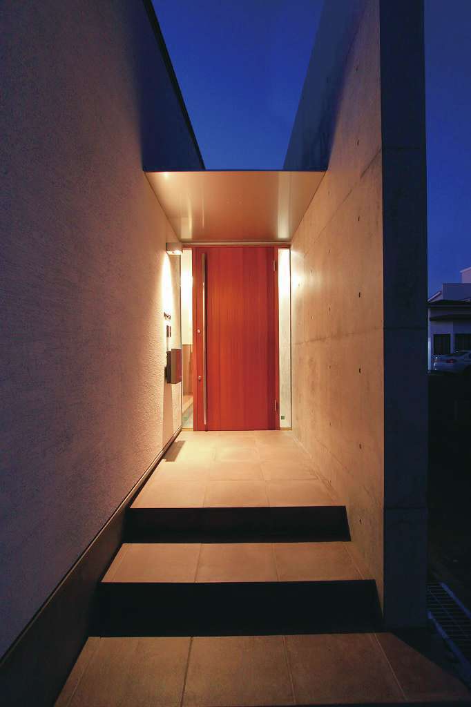 神谷綜合建設 カミヤの家【デザイン住宅、収納力、二世帯住宅】赤褐色のサぺリを使った製作建具とコンクリート壁の玄関は、まるで小さな美術館のエントランスのよう