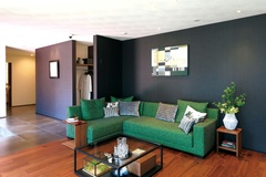 シックな色合いのリビングルーム。緑のソファが落ち着いた雰囲気を演出しており、アート作品がアクセントになっています。