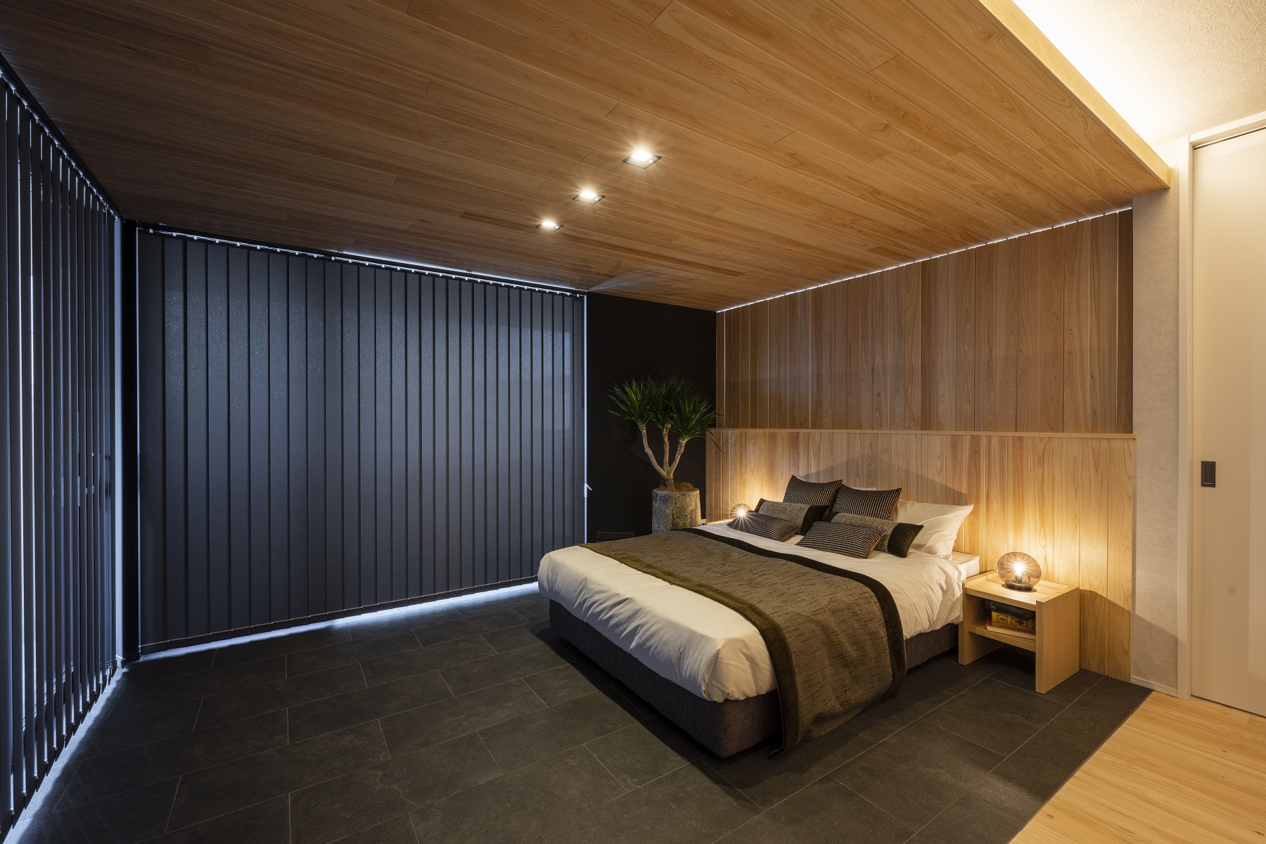 日本ハウスホールディングス 岐阜｜シンプルでモダンなデザインの寝室。暖かみのある木の天井と落ち着いた色調の内装がリラックスした雰囲気を演出している。