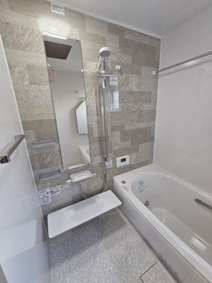 モダンで機能的なバスルーム。壁面には落ち着いた色調のタイルが施され、シャワーとバスタブがすっきりと配置されている。リラックスした時間を提供する空間である。