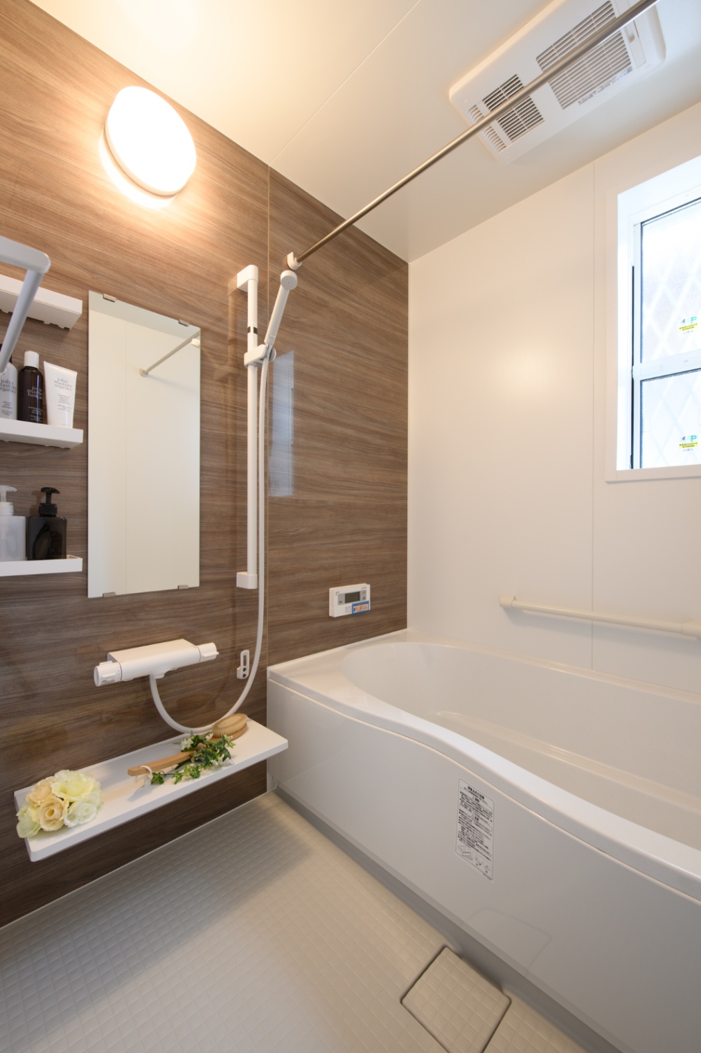 Sus∞Eco Home（サスエコホーム）｜モダンなデザインのバスルーム。木目調の壁パネルと白を基調とした清潔感のある空間で、リラックスできる心地よい浴槽が設置されている。