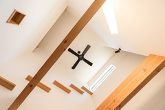 吹き抜けに設けられたキャットウォークは、二階と一階をゆるやかにつなぐ遊び心のあるデザイン。高窓からの光が梁にやわらかく広がり、猫も家族も心地よく過ごせそうな空間です。