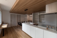 天井に木材を使用したデザイン性の高いキッチン。オープンな作りが特徴で、リビング・ダイニングと一体感を持たせる工夫がされている。